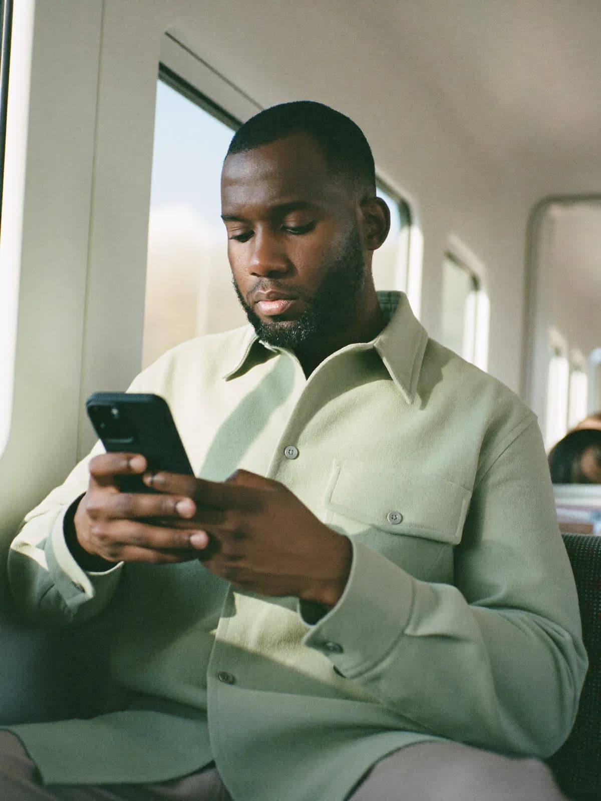 A man on a train, reading his phone